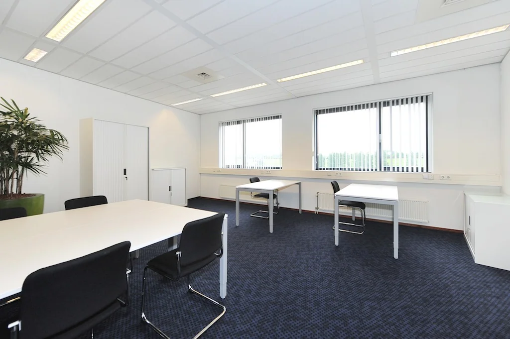 Licht en modern kantoor aan de Laan van s-Gravenmade met bureaus, stoelen en grote ramen met verticale lamellen.